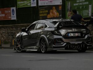 A sleek, customized Honda Civic car on city streets with urban backdrop.
